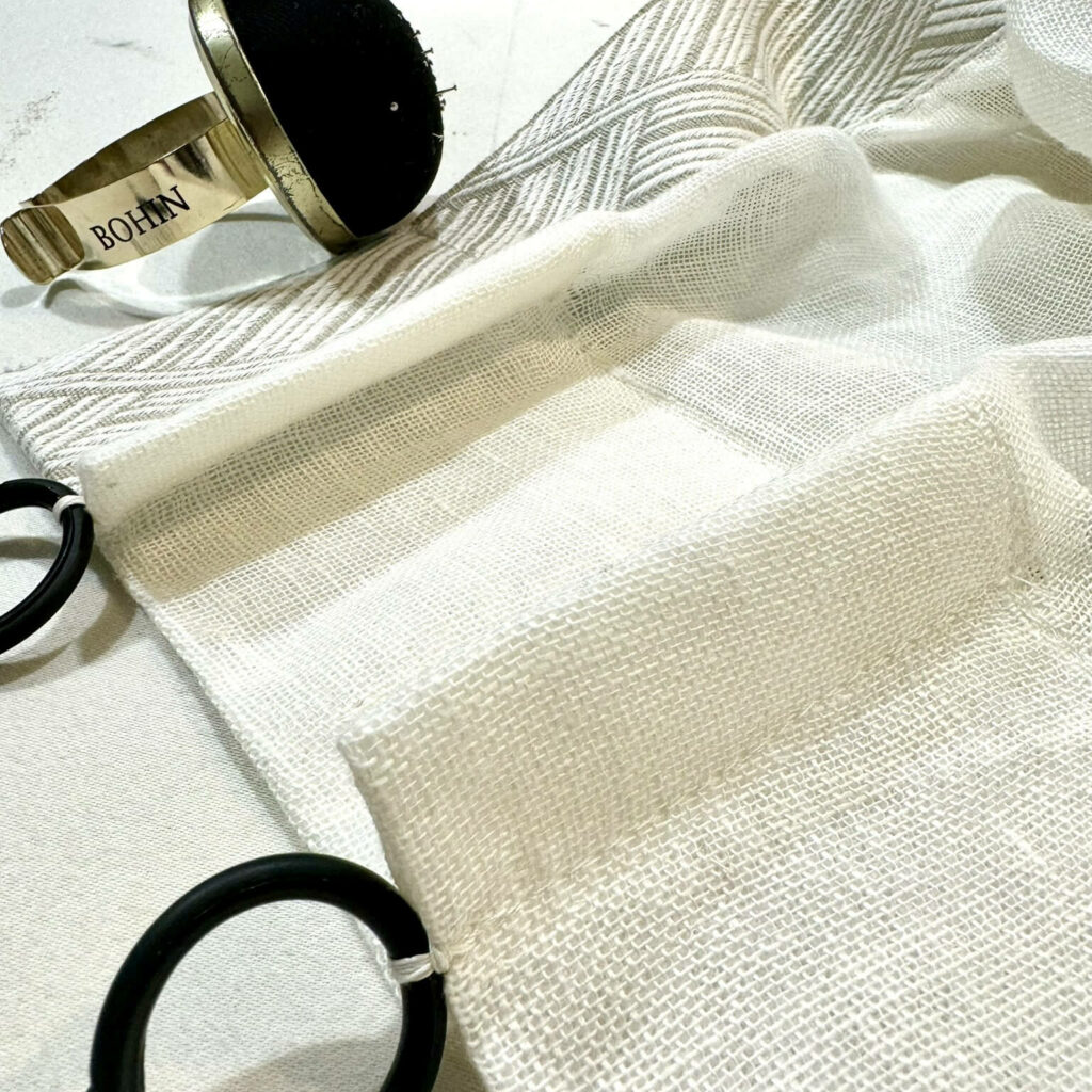 rideaux en voile de lin beige et passementerie, plis simple et anneaux fer forgés cousus main pour filtrer la lumière